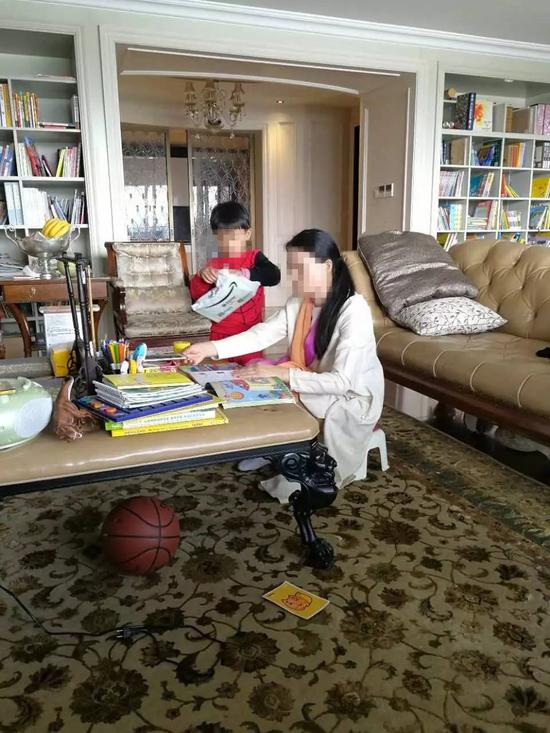 朱小貞和小兒子在客廳里，背后書架為起火點。（受訪者供圖）